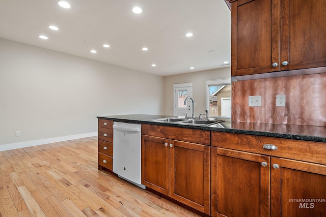 kitchen featuring light wood finished floors, dark countertops, recessed lighting, a sink, and dishwasher