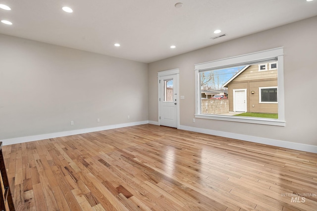 empty room with light wood-style floors, recessed lighting, visible vents, and baseboards