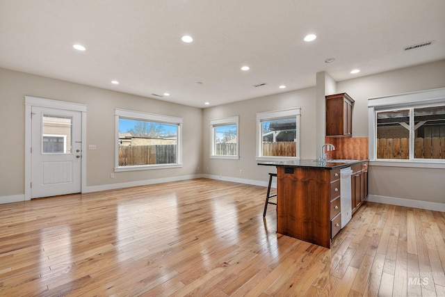 kitchen featuring light wood-style floors, a sink, visible vents, and a kitchen breakfast bar