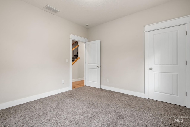 unfurnished bedroom featuring carpet floors, baseboards, visible vents, and a closet