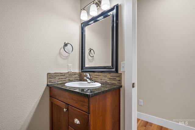 bathroom with baseboards, backsplash, vanity, and wood finished floors