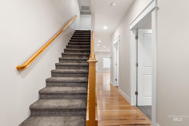 staircase featuring baseboards, visible vents, wood finished floors, and recessed lighting