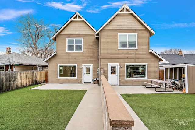 rear view of property featuring a patio, fence, and a lawn