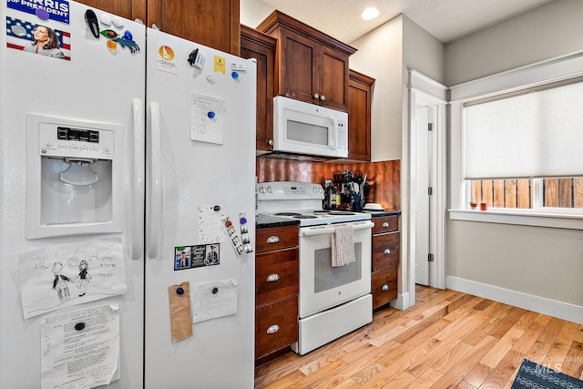 kitchen featuring dark countertops, white appliances, light wood-type flooring, and baseboards