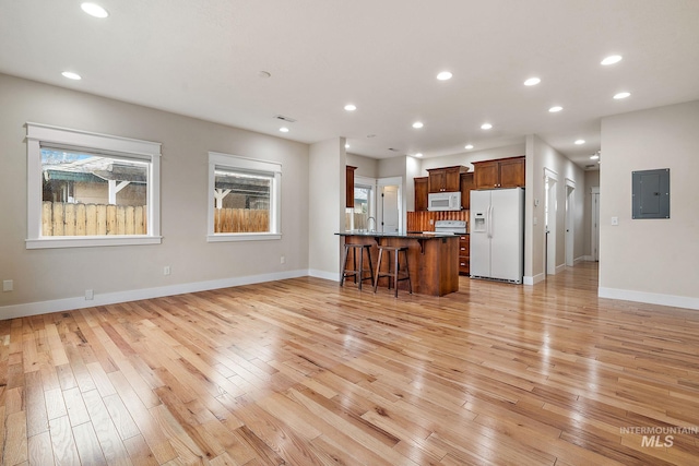 unfurnished living room with light wood finished floors, electric panel, baseboards, and recessed lighting