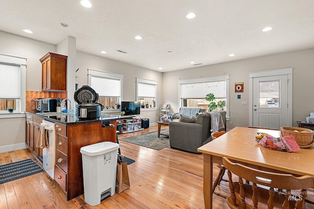 kitchen with light wood-style floors, brown cabinetry, a sink, and recessed lighting