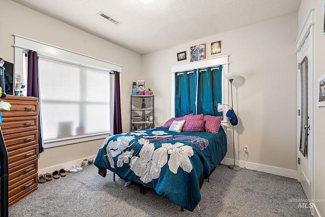 carpeted bedroom with baseboards, visible vents, and a textured ceiling