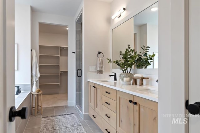 full bathroom featuring a sink, double vanity, a shower stall, and tile patterned flooring