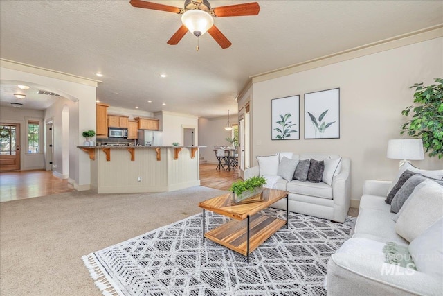 2895 E Shadowwolf Dr, Eagle, ID 83616 - living room featuring light carpet, crown molding, a ceiling fan, arched walkways, and recessed lighting