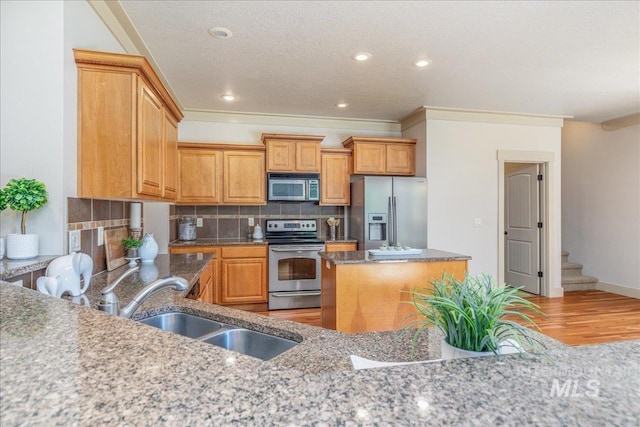 2895 E Shadowwolf Dr, Eagle, ID 83616 - kitchen with appliances with stainless steel finishes, light wood finished floors, a kitchen island, decorative backsplash, and stone countertops
