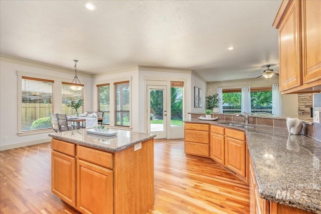 2895 E Shadowwolf Dr, Eagle, ID 83616 - kitchen featuring light wood-style floors, light stone countertops, hanging light fixtures, recessed lighting, and ornamental molding