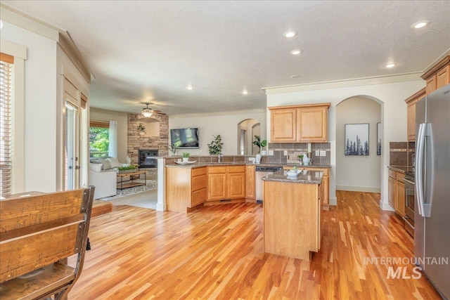 2895 E Shadowwolf Dr, Eagle, ID 83616 - kitchen featuring stainless steel appliances, arched walkways, a peninsula, a fireplace, and open floor plan