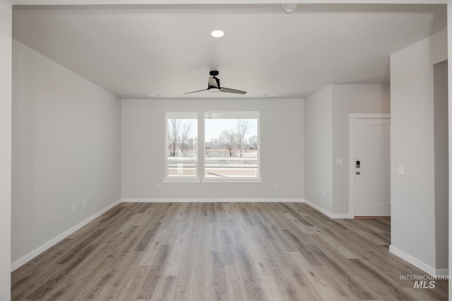 unfurnished room with baseboards, a ceiling fan, and light wood-style floors