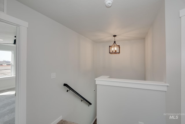 staircase featuring a chandelier, carpet flooring, and baseboards