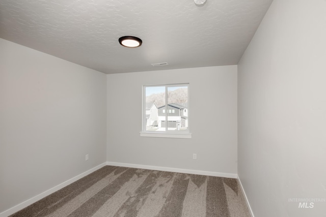 unfurnished room featuring baseboards, a textured ceiling, visible vents, and carpet flooring