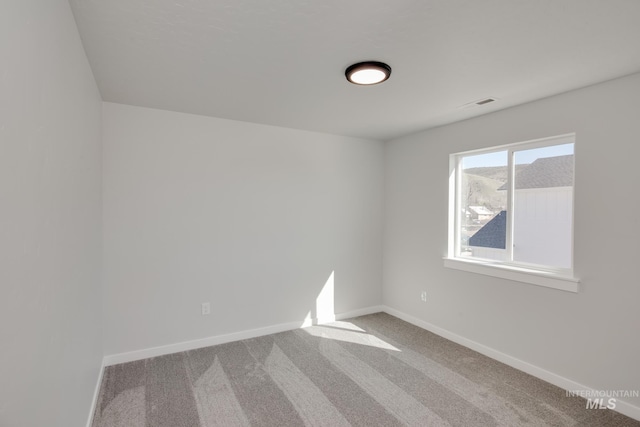 unfurnished room with carpet floors, visible vents, and baseboards