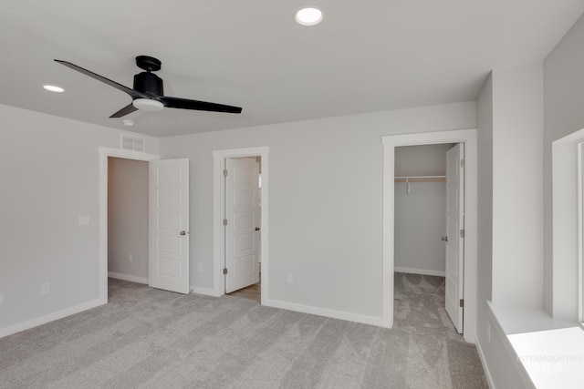 unfurnished bedroom featuring baseboards, a walk in closet, light colored carpet, and recessed lighting