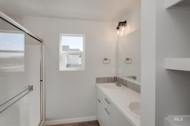 bathroom with a sink, double vanity, and a shower with shower door