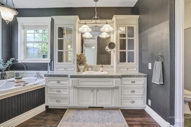 930 W Wanda Ln, Heyburn, ID 83336 - bathroom with wood finished floors, vanity, toilet, baseboards, and a garden tub
