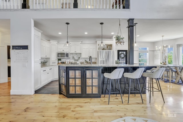 930 W Wanda Ln, Heyburn, ID 83336 - kitchen featuring stainless steel appliances, a breakfast bar, white cabinets, tasteful backsplash, and light wood-style floors