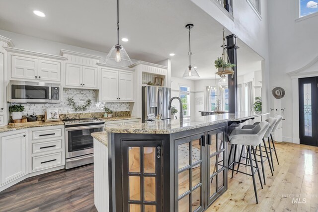 930 W Wanda Ln, Heyburn, ID 83336 - kitchen with stainless steel appliances, white cabinets, backsplash, a breakfast bar, and a large island with sink