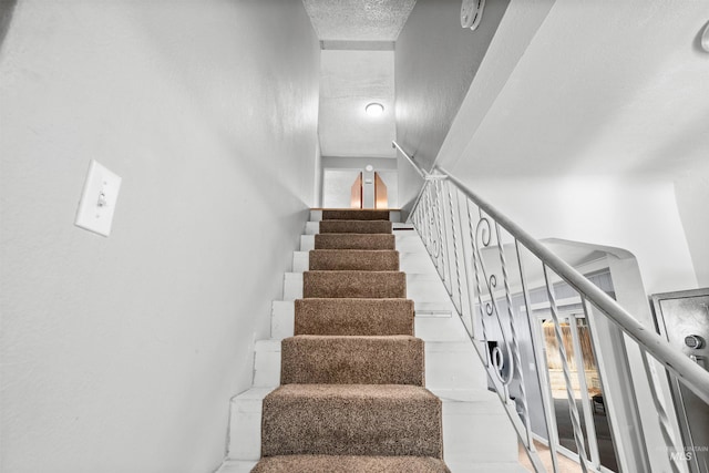 stairs featuring a textured ceiling