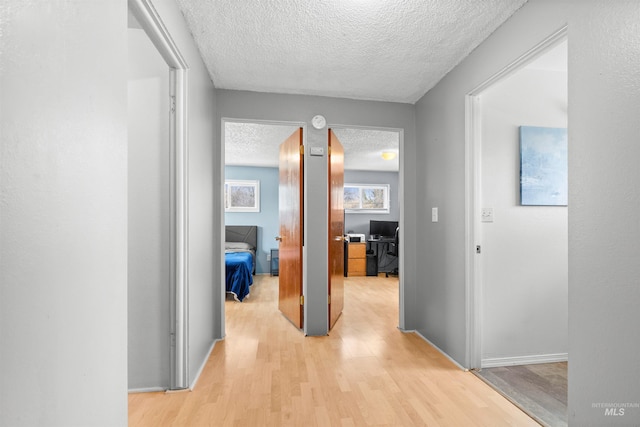 hall with light hardwood / wood-style flooring and a textured ceiling