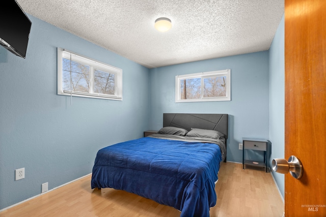 bedroom with light hardwood / wood-style flooring and a textured ceiling