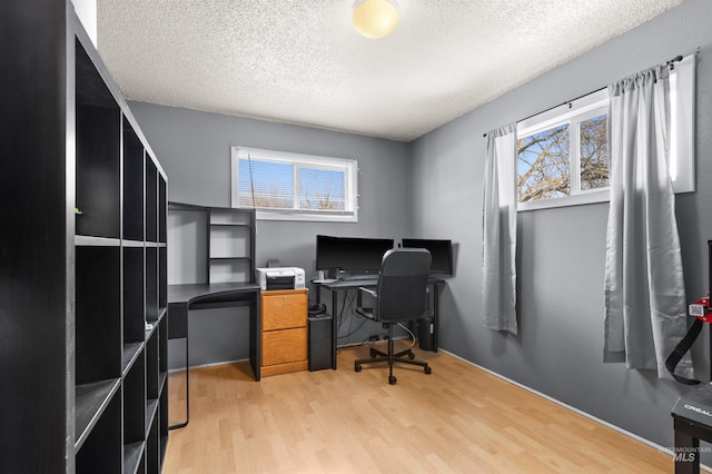 office featuring a textured ceiling, light hardwood / wood-style flooring, and a healthy amount of sunlight