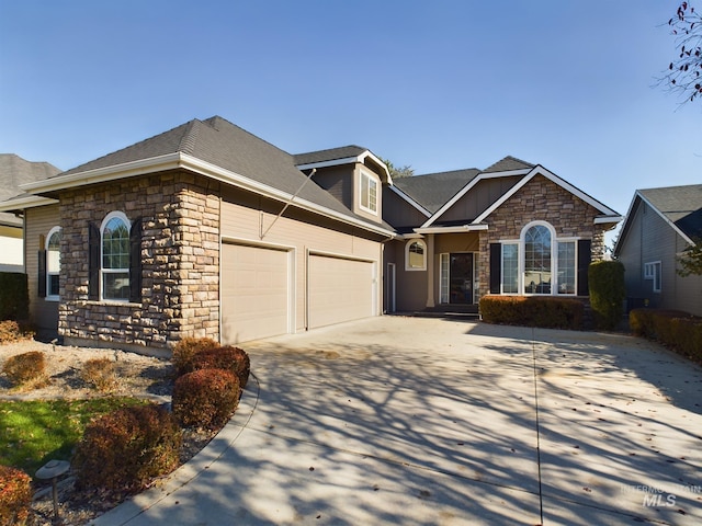 view of front of property featuring stone siding, roof with shingles, concrete driveway, and an attached garage