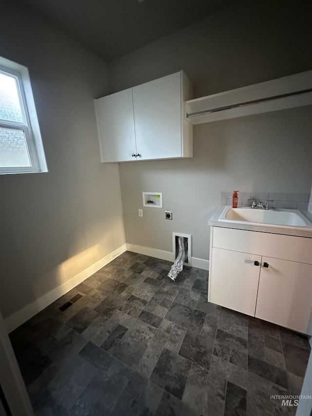 laundry room with hookup for a washing machine, hookup for an electric dryer, cabinet space, baseboards, and dark stone finish floors