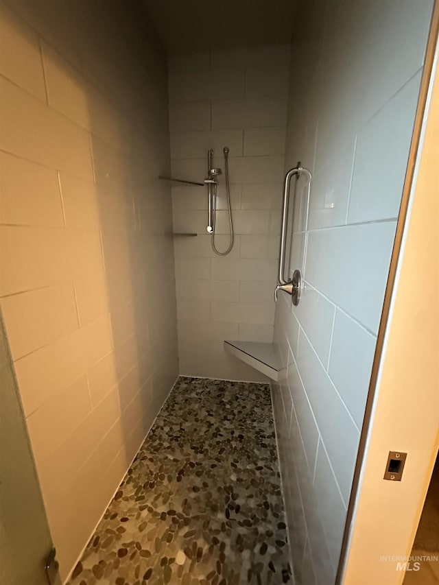bathroom featuring tiled shower and stone finish floors
