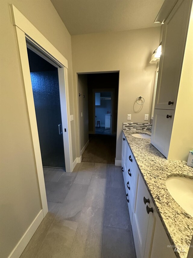 bathroom with double vanity and baseboards