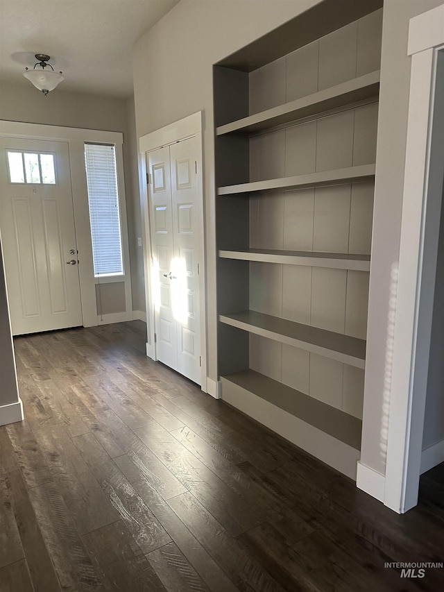 foyer with dark wood finished floors and baseboards