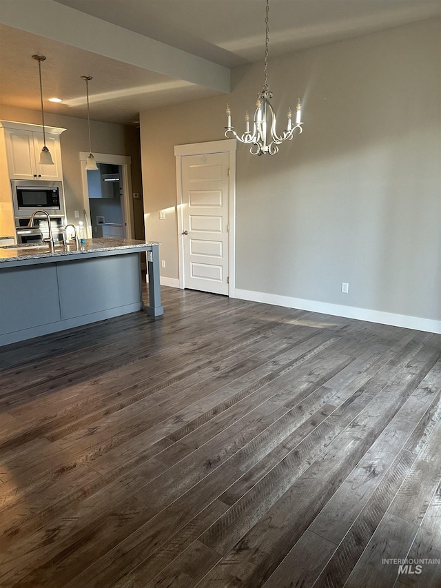kitchen featuring stainless steel microwave, dark wood-style flooring, a chandelier, and baseboards