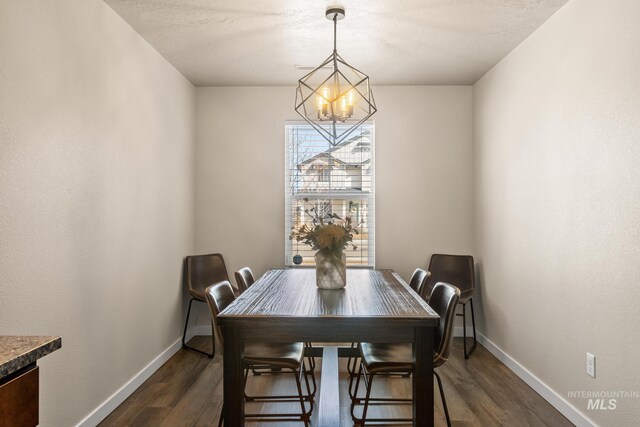 dining space with dark wood finished floors, a notable chandelier, and baseboards