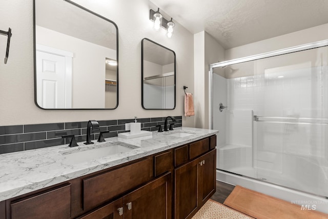 full bath with a sink, double vanity, and a shower stall