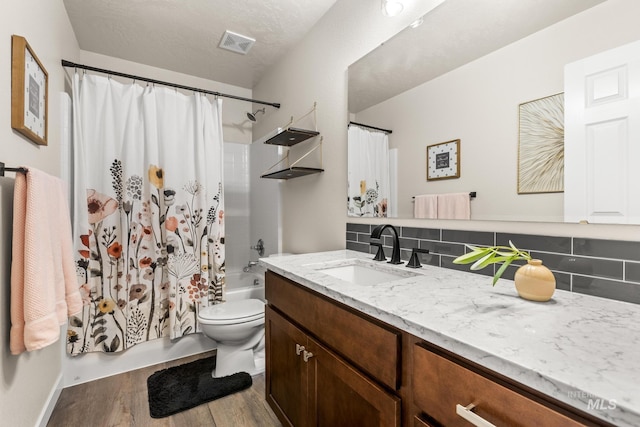 full bathroom featuring visible vents, shower / tub combo with curtain, wood finished floors, decorative backsplash, and vanity