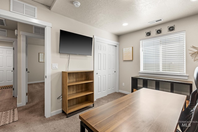 carpeted office space with baseboards, visible vents, and a textured ceiling