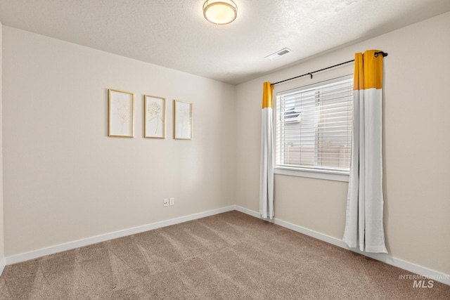 carpeted empty room featuring visible vents, a textured ceiling, and baseboards