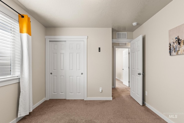 unfurnished bedroom with visible vents, baseboards, carpet floors, a closet, and a textured ceiling