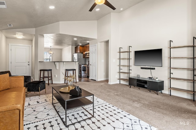 carpeted living area featuring recessed lighting, baseboards, high vaulted ceiling, and ceiling fan with notable chandelier