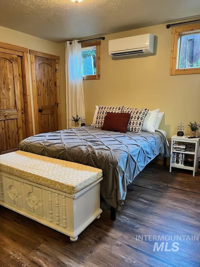 bedroom featuring a wall mounted air conditioner and dark wood-style flooring