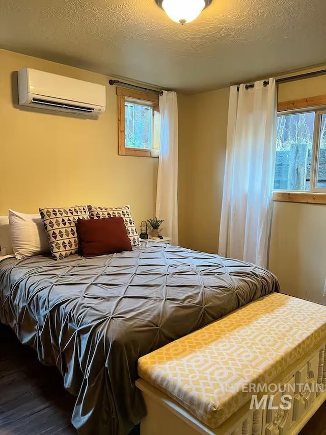 bedroom featuring a textured ceiling, a wall mounted AC, and wood finished floors