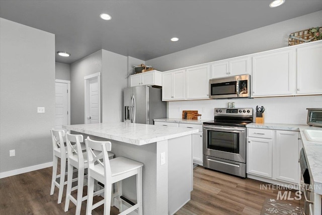kitchen with stainless steel appliances, white cabinets, dark wood-style floors, and a center island