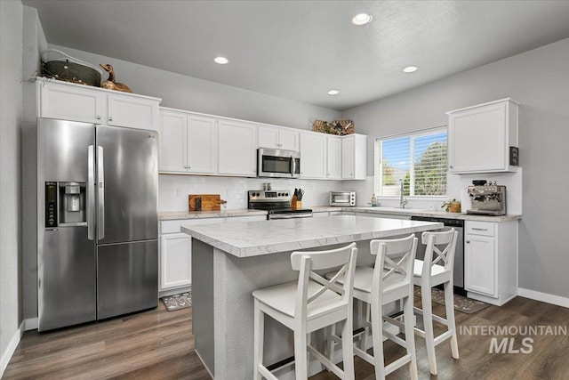 kitchen with dark wood-style flooring, white cabinets, appliances with stainless steel finishes, and light countertops
