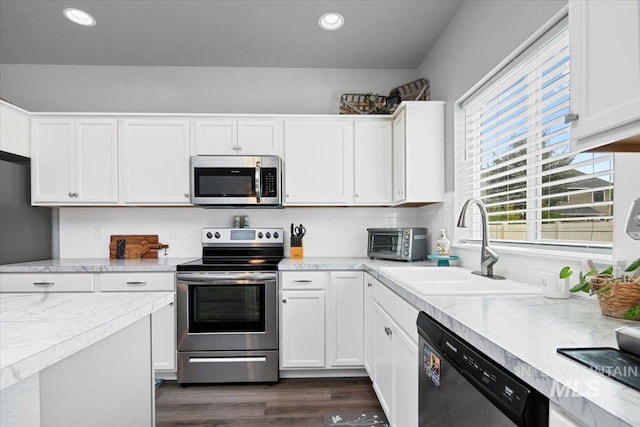 kitchen with dark wood finished floors, a toaster, stainless steel appliances, a sink, and white cabinetry