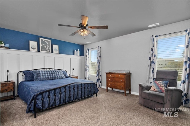 bedroom featuring carpet, visible vents, a ceiling fan, and wainscoting