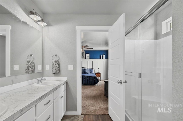 full bath featuring a stall shower, ceiling fan, vanity, and ensuite bath
