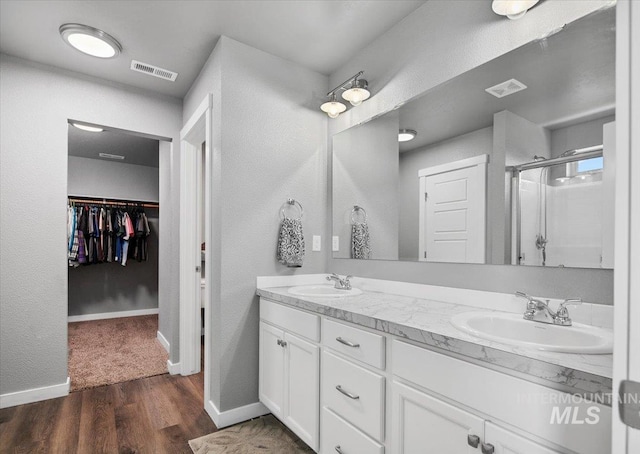 full bathroom featuring visible vents, a stall shower, double vanity, and a sink